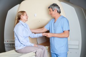 Male radiologic technician comforting female patient before MRI scan